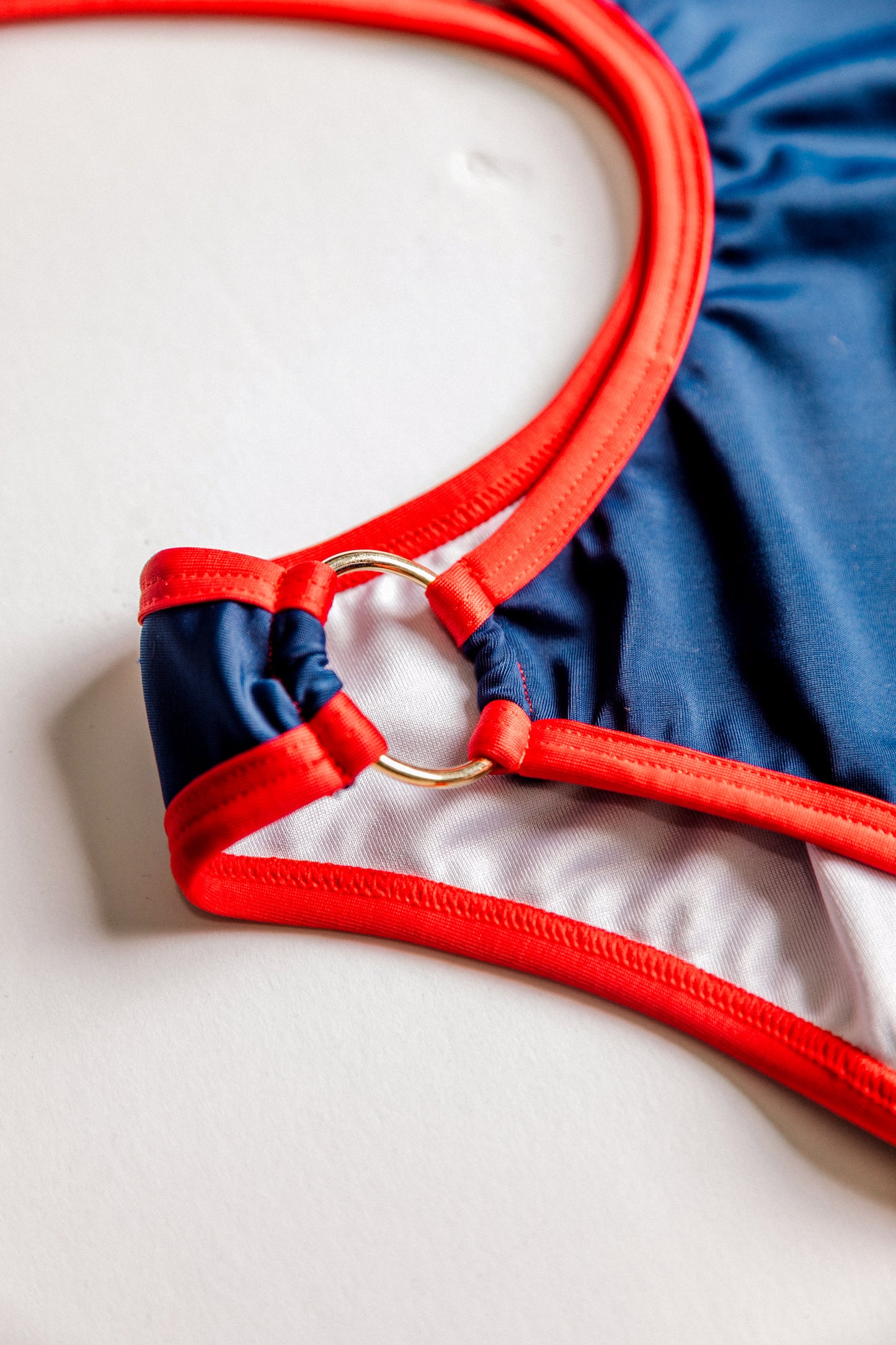 Boomerang one-piece swimsuit in navy with red, ring detail close-up – Bikini Uni