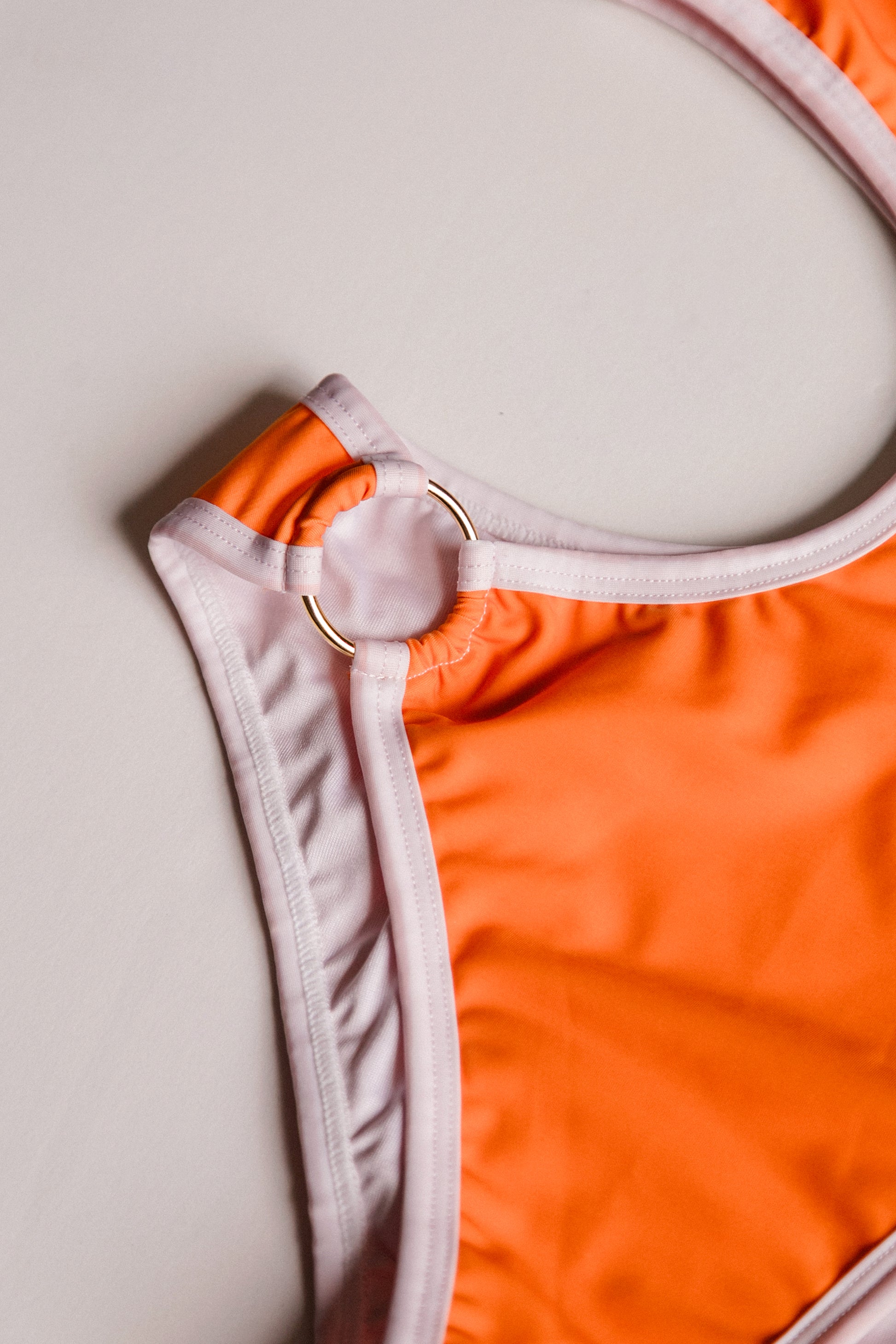 Boomerang one-piece swimsuit in orange with white, ring detail close-up – Bikini Uni