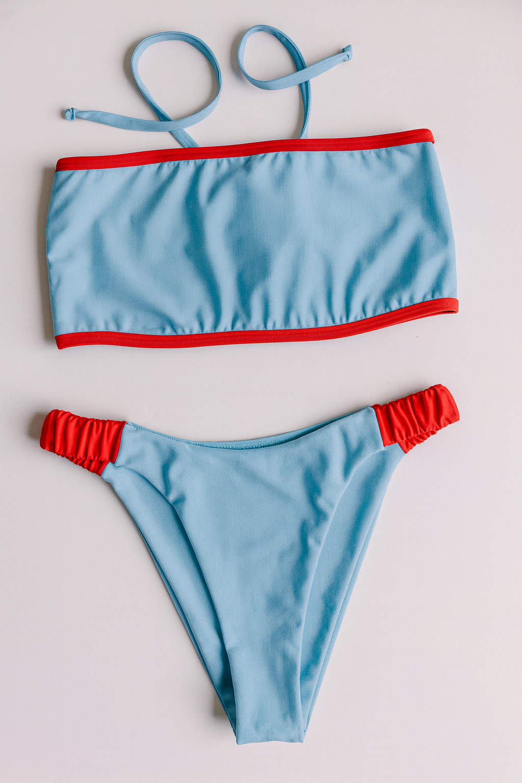 Dos Tierras two-piece bikini in light blue with red, front flatlay view – Bikini Uni