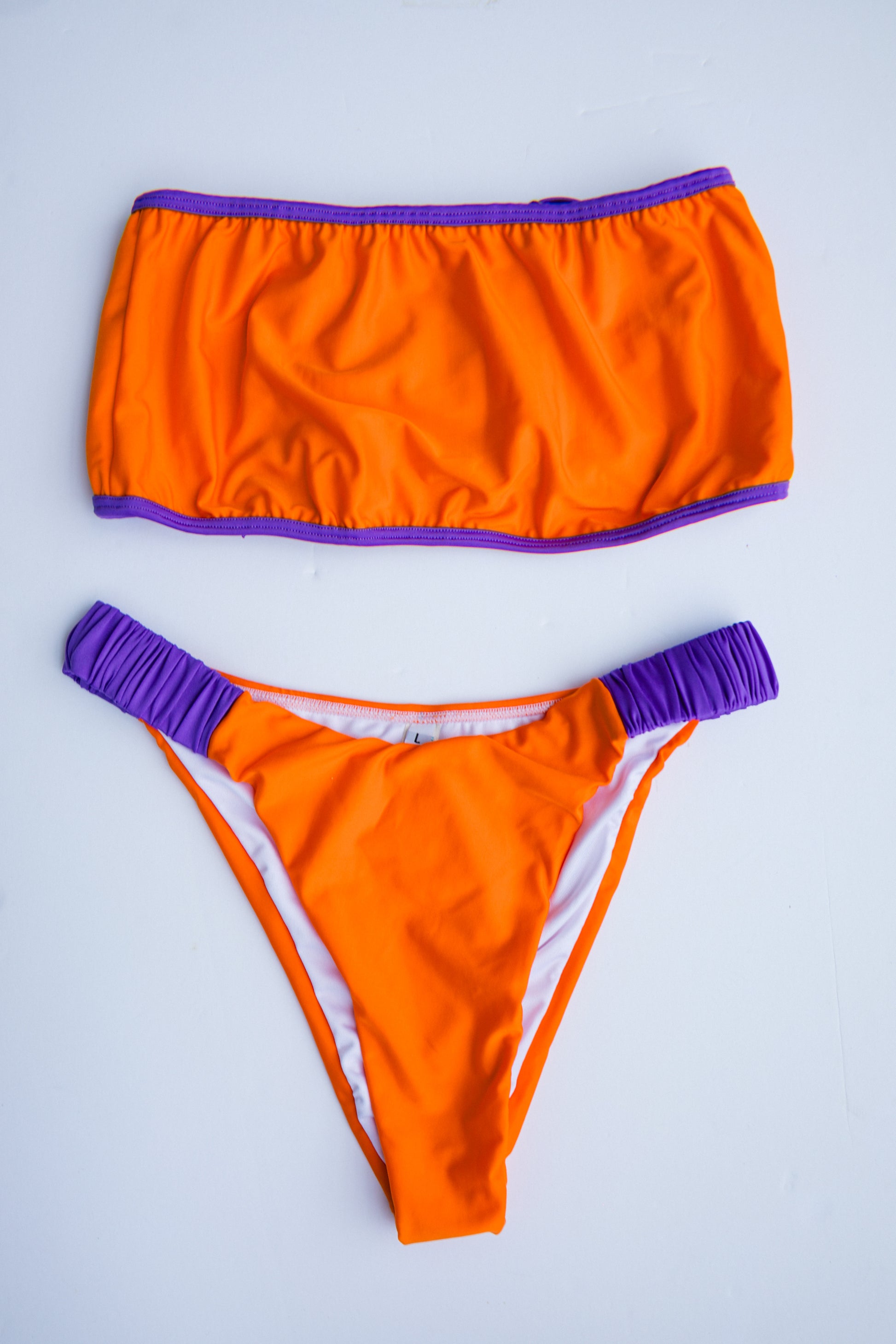 Dos Tierras two-piece bikini in orange with purple, front flatlay view – Bikini Uni