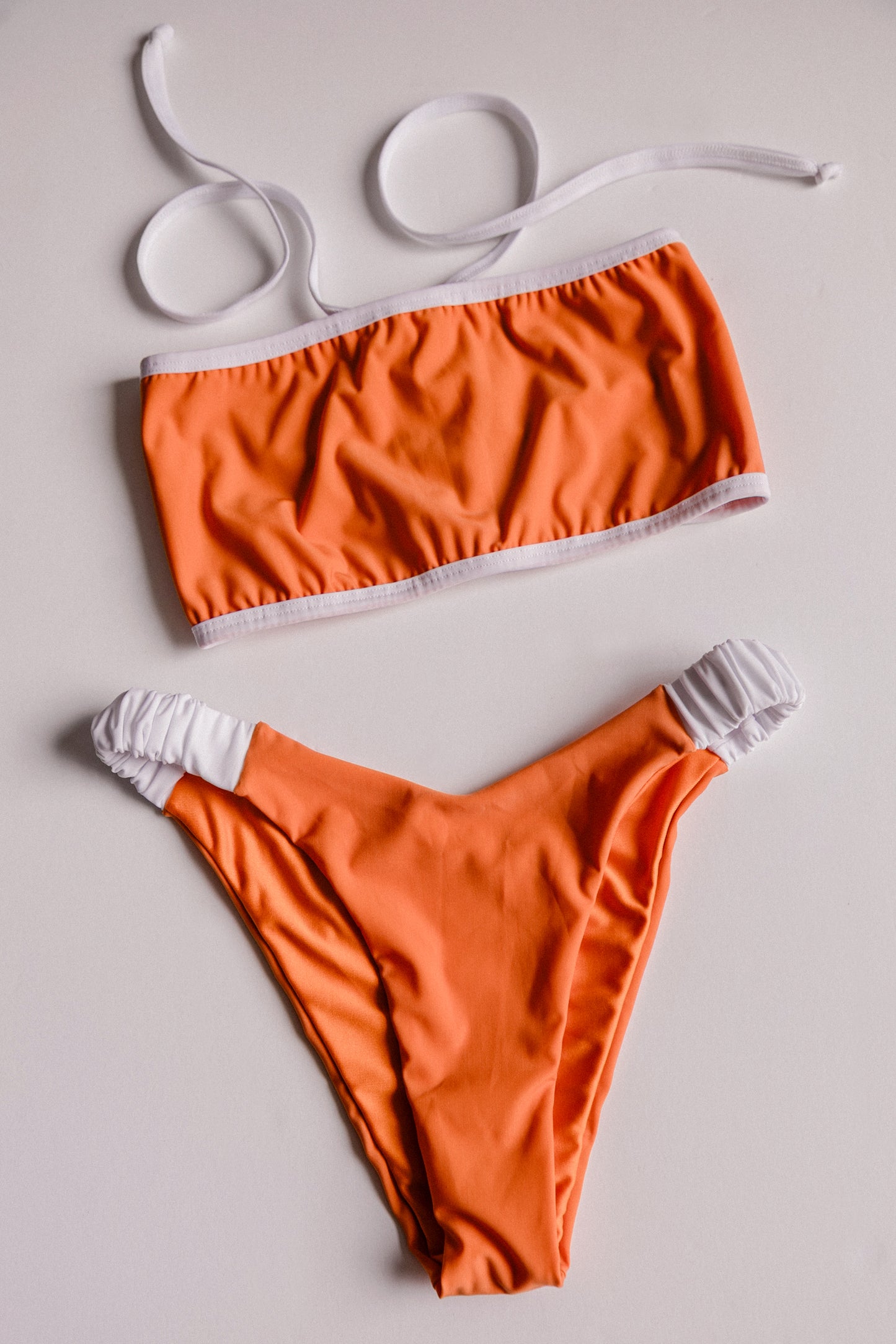 Dos Tierras two-piece bikini in orange with white, front flatlay view – Bikini Uni