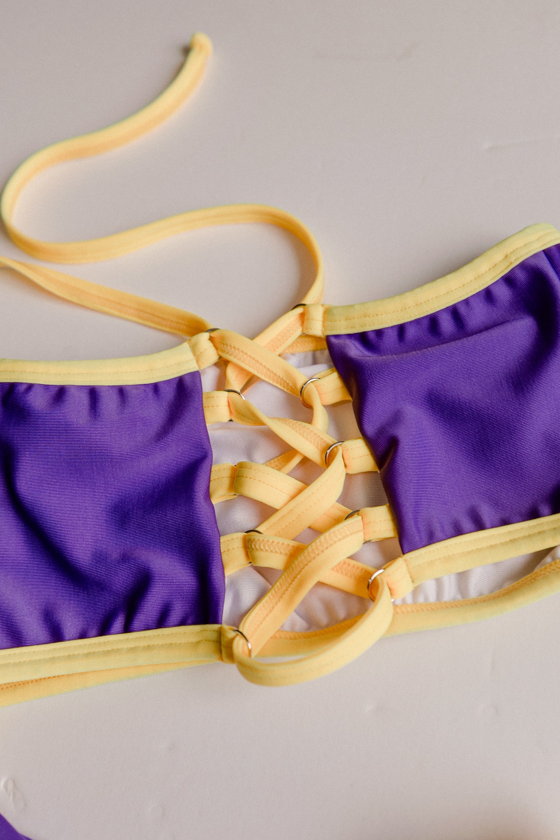 Dos Tierras two-piece bikini in purple with gold, lace-up detail close-up – Bikini Uni