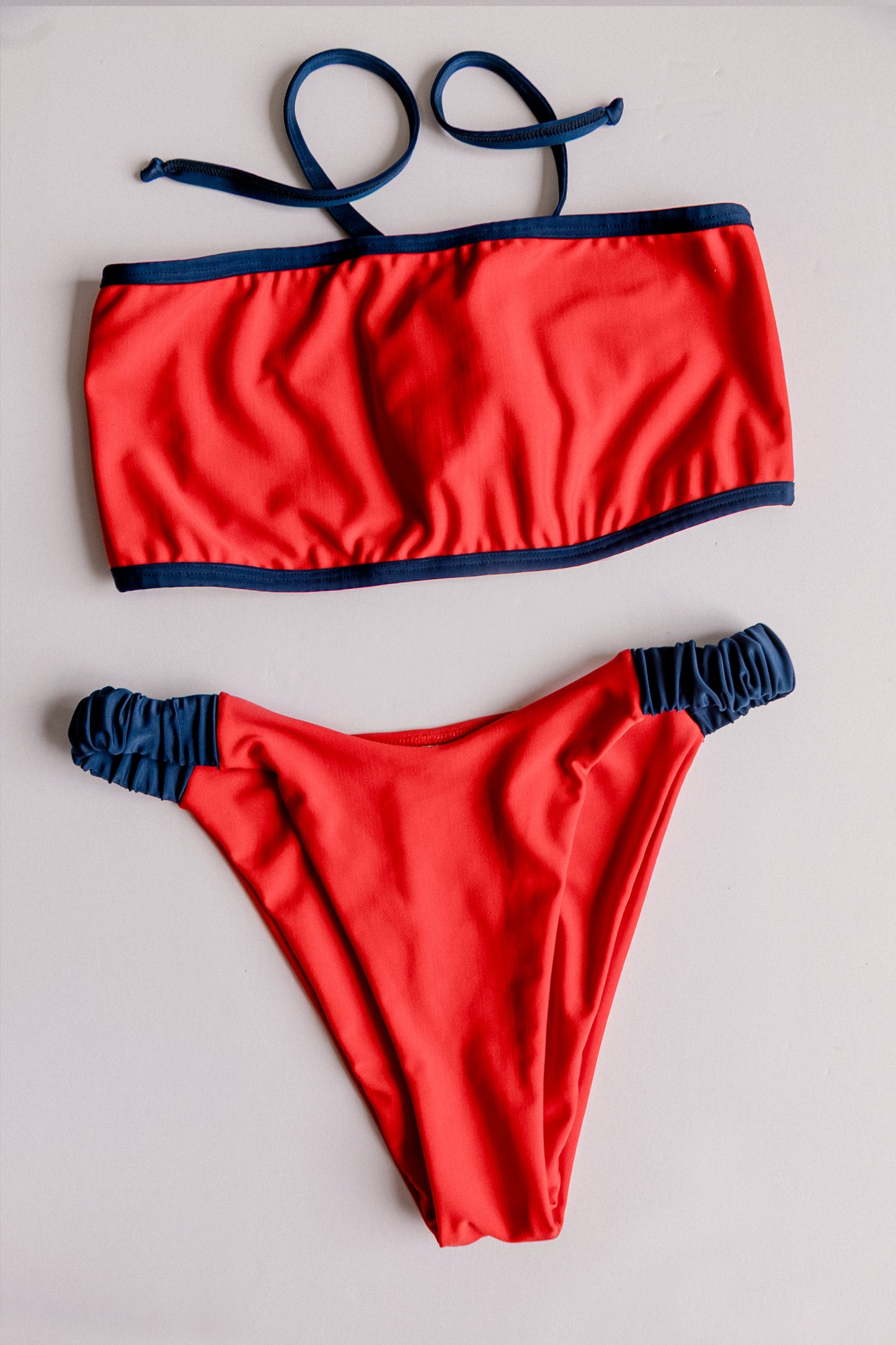 Dos Tierras two-piece bikini in red with navy, bandeau top flatlay view – Bikini Uni